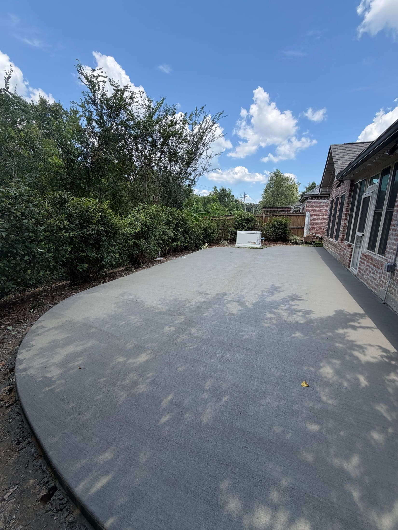 The same curved patio finished: broom-textured concrete along the brick home