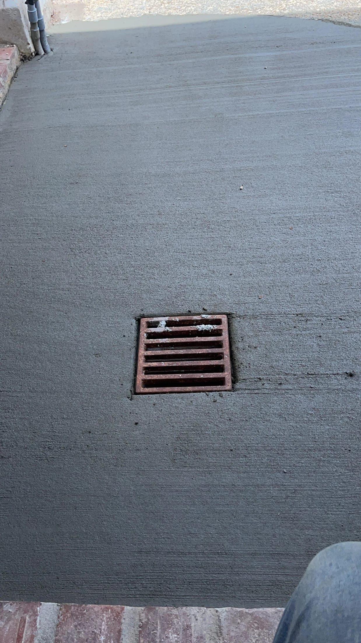 Cast iron drain grate set flush in a freshly finished concrete slab