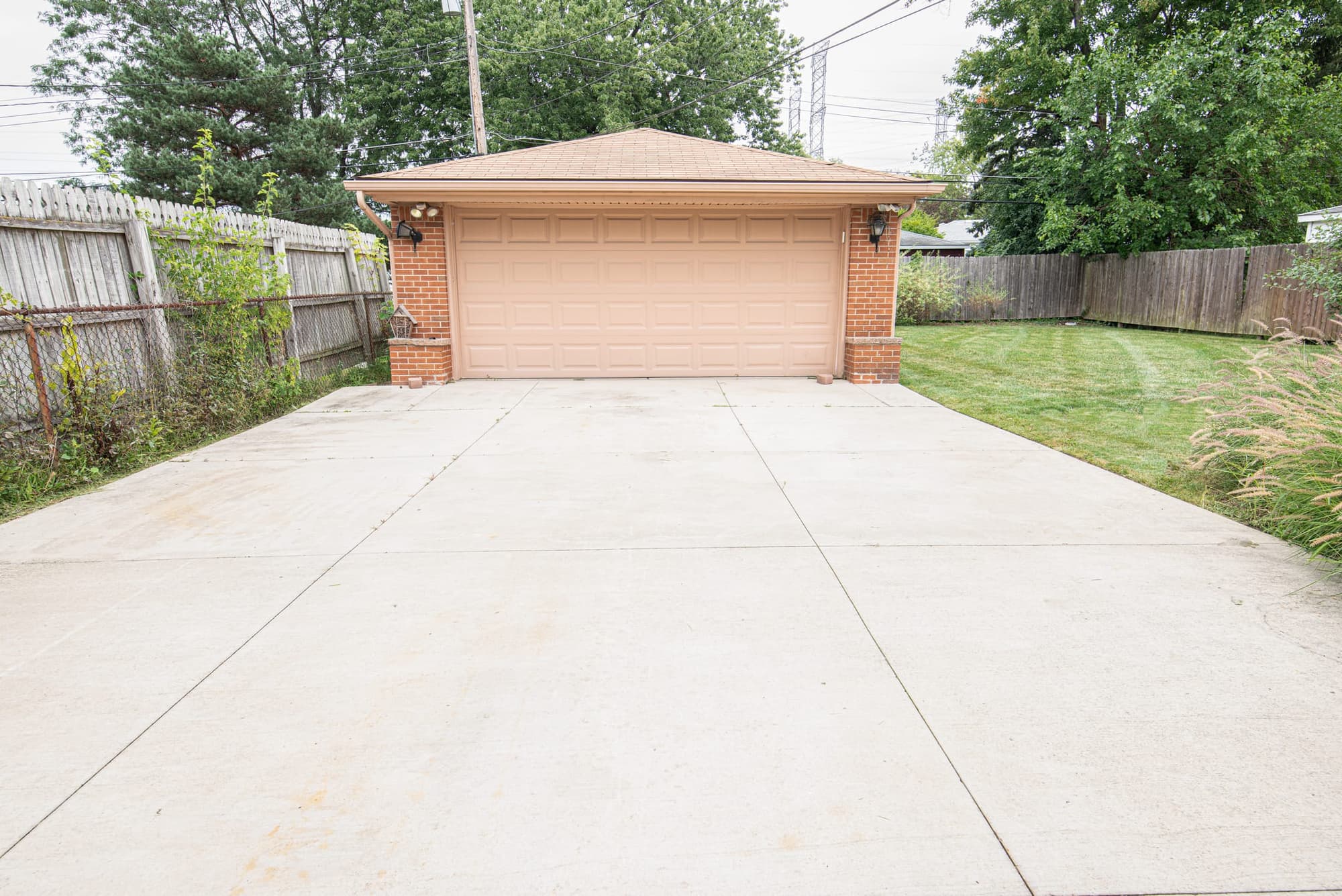 Clean concrete driveway leading to a detached brick garage