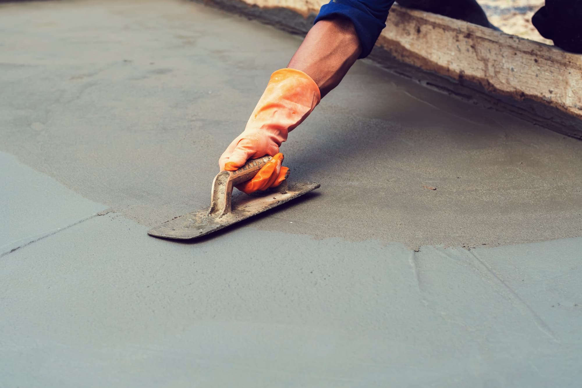 Steel hand trowel finishing a fresh slab next to the wood form