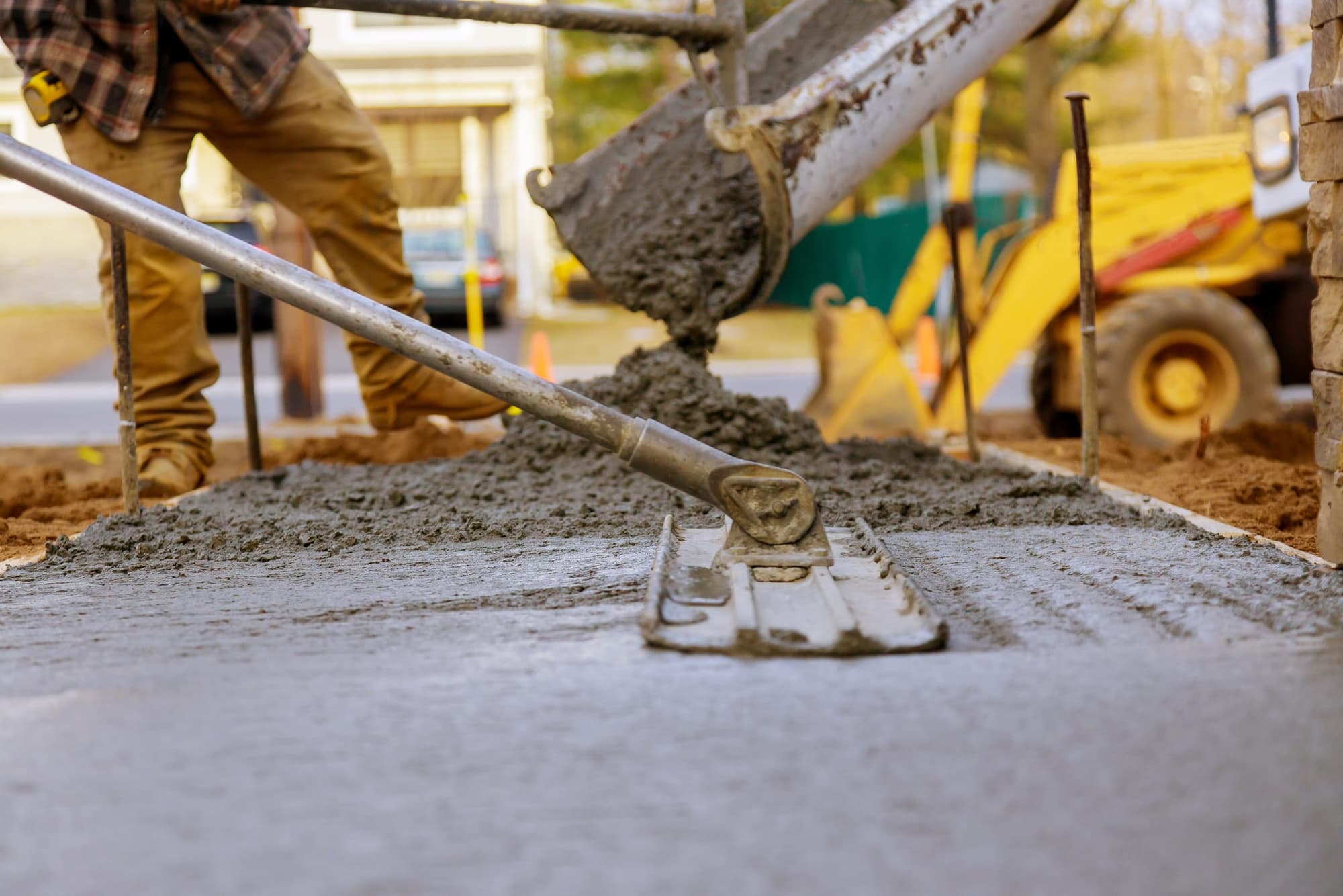 Concrete pouring from a mixer chute while a finisher floats the slab